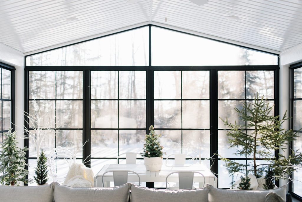 sunroom decorated for christmas with trees and greens