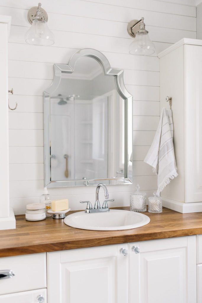 A bathroom sink with large silver mirror above