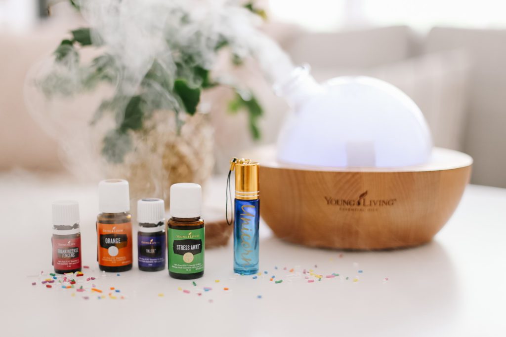 essential oils and a roller in front of a Young Living Aria diffuser