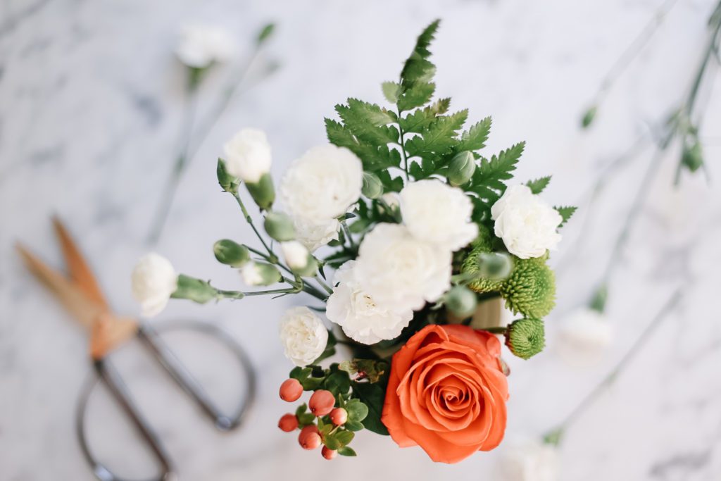 Orange rose, berries and white carnation flower arrangement