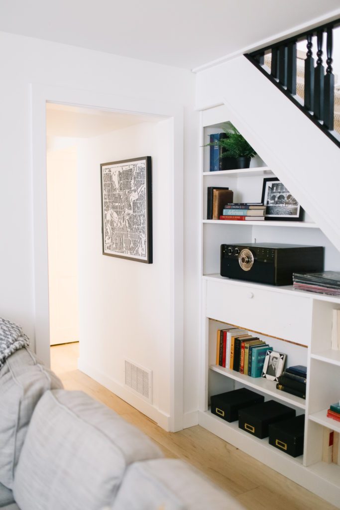 Built in shelving under the stairs with books and art